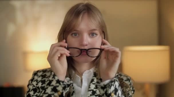 Primer plano de la mujer guapa feliz en Glassess mirando a la cámara. Retratos de personas. Concepto de emociones. Fondo borroso de oficina . — Vídeos de Stock