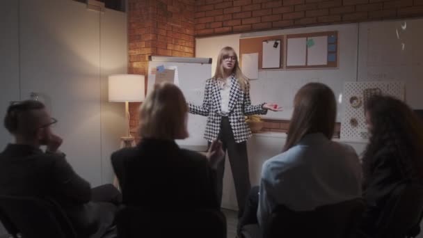 Kvinnlig chef presenterar ny projektplan för kollegor vid mötet, förklara idéer om blädderblock till medarbetare på kontoret, affärskvinna ger presentation — Stockvideo