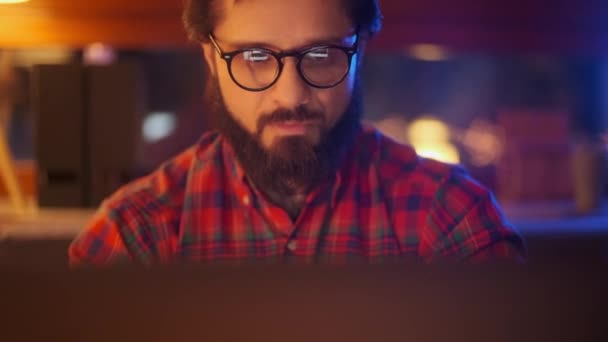 Retrato de un hombre está trabajando en el ordenador portátil con gafas en la noche. De cerca. Empresario mirando monitor, reflexiones en gafas, comerciante de la bolsa masculina usando el ordenador portátil en la oficina . — Vídeo de stock