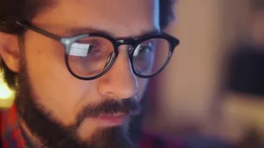 Ofisinde gece geç saatlere kadar çalışıp bilgisayarında monitöre bakan gözlüklü genç bir iş adamının yakın portresi. Bilgisayar Ekranı Gözlüklerine Yansıyor.