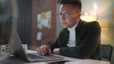 Bir adamın portresi geceleri gözlüklerle dizüstü bilgisayarda çalışıyor. Gece geç saatlere kadar çalışan işadamı, monitöre bakıyor, gözlüklü yansımalar, ofiste dizüstü bilgisayar kullanan erkek borsa simsarı....