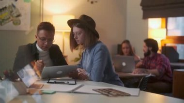 Genç Şık Tasarımcılar, Bir Tablet Üzerinde Dizüstü Bilgisayarlı Kalem, Arkaplan Kadın ve Erkek Çizerek Bir Proje Tartışıyor.