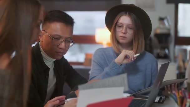 Jóvenes diseñadores con estilo están discutiendo un proyecto en una tableta dibujando con una pluma, fondo femenino y masculino con computadora portátil . — Vídeo de stock