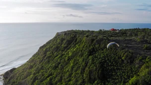 Параплэйн, лидер в воздушном бою. "Extreme Man Flies On a Paraglider Over a Cliff Near The Sea". Жизнь на Бали, Индонезия . — стоковое видео