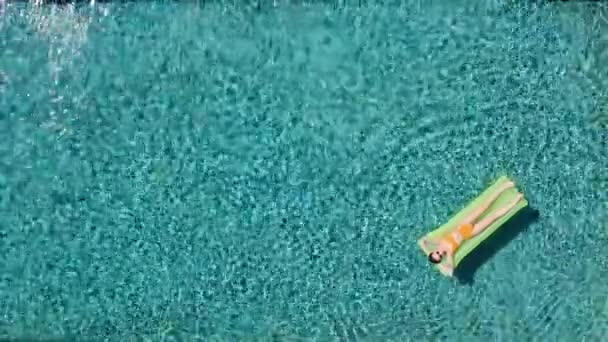 Mulher atraente em flutuador verde inflável na piscina desfrutando de verão relaxante em férias vestindo biquíni amarelo sexy vista superior — Vídeo de Stock
