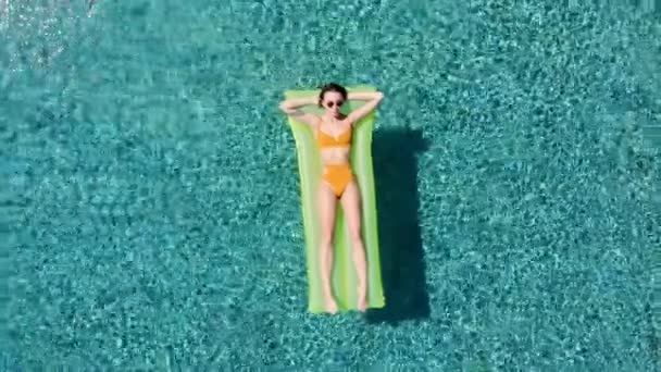 Sexy mujer Descanse y tomar el sol en un flotador verde en la piscina, tiro aéreo de vista superior. Mujer joven en un traje de baño amarillo del bikini que flota en una vista superior amarilla inflable del colchón — Vídeos de Stock