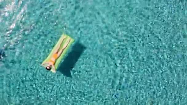 Aerial - Dorosły mężczyzna nurkuje do basenu, podczas gdy dziewczyna pływa na czuwaniu materac i śmieje. — Wideo stockowe