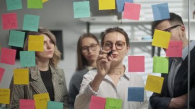 Yaratıcı İş Adamları Beyin Fırtınası Fikirleri Yapışkan Notlarla Cam Duvar 'ın yanında birlikte çalışıyorlar. Meslektaşlar onaylıyor. İş Başarı Konsepti
