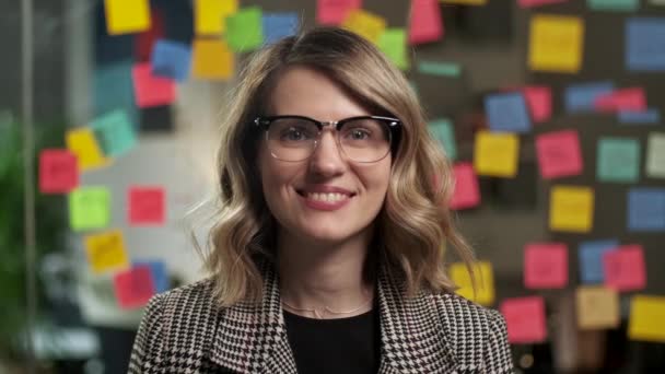 Portrait of Beautiful Young Woman with Blond Hair Wearing Yellow Sweater Looking Up to the Camera and Smiling Charmingly. Successful Woman Working in Bright Diverse Office — Stock Video