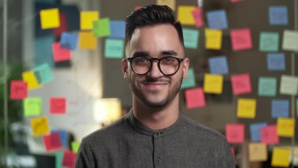 Nahaufnahme Porträt eines jungen attraktiven, gutaussehenden Geschäftsmannes mit Brille, der selbstbewusst in die Kamera lächelt — Stockvideo