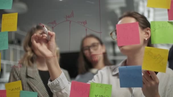 Δημιουργική Business Team Brainstorming Ιδέες Δουλεύοντας μαζί κοντά στο γυάλινο τοίχο με αυτοκόλλητες σημειώσεις. Οι συνάδελφοι το εγκρίνουν. Έννοια επιχειρηματικής επιτυχίας — Αρχείο Βίντεο