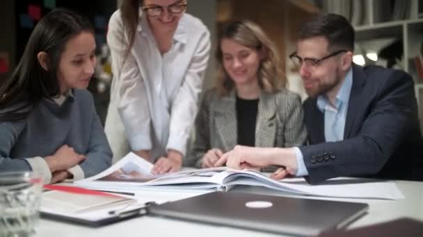 Colleghi e clienti che parlano di strategia con Project Magazine. In Creative Office Productive Coworkers in piedi al tavolo per la riunione aziendale. Lavoro di squadra e concetti speciali — Video Stock