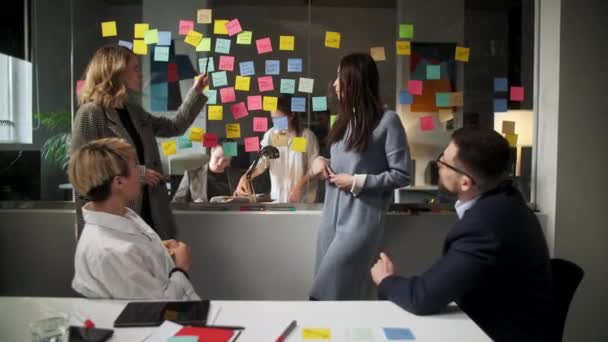 クリエイティブ・ビジネス・チームスティッキーノートでガラスの壁の近くで一緒に働くアイデアをブレーンストーミング.同僚が承認する。事業成功コンセプト — ストック動画