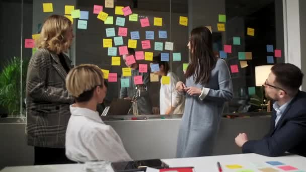 Creative Business Team Idee di brainstorming che lavorano insieme vicino alla parete di vetro con appunti appiccicosi. I colleghi approvano. Concetto di successo aziendale — Video Stock