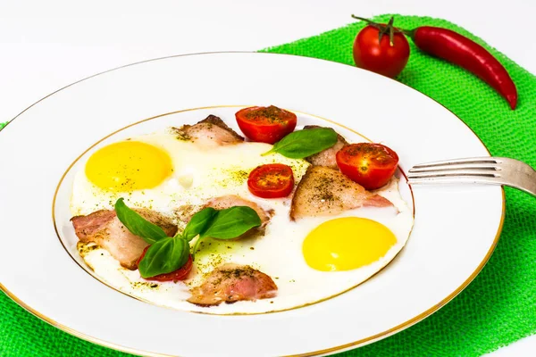 Fried eggs with bacon and vegetables on a white plate — Stock Photo, Image
