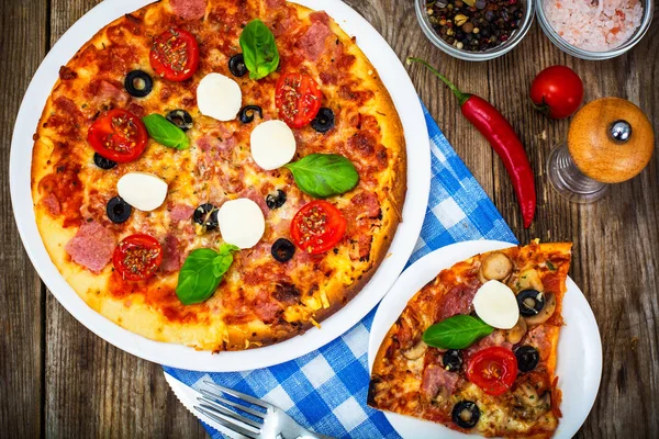 Italian pizza with ham, cheese, mushrooms, tomatoes and mozzarel Stock Photo