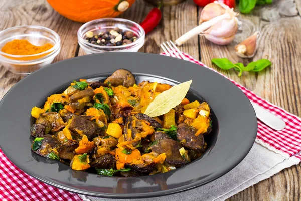 Жареные овощи с тыквой и грибами на черной тарелке — стоковое фото