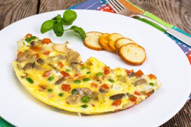 Yarım omlet beyaz bir tabakta sebze ile