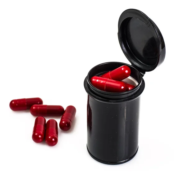 Червона капсула медичної банки в чорному кольорі на білому тлі — стокове фото