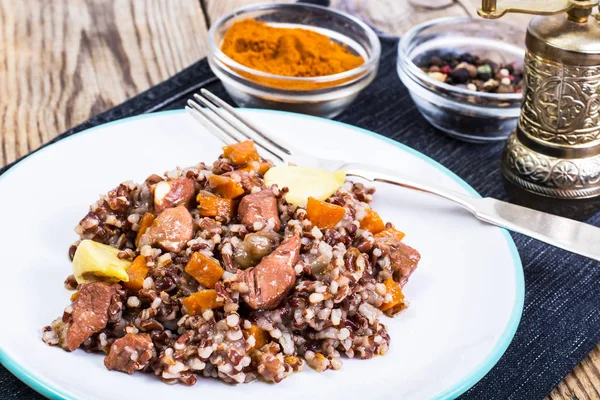 Pilaf com arroz vermelho com pedaços de carne bovina, cenoura e alho — Fotografia de Stock