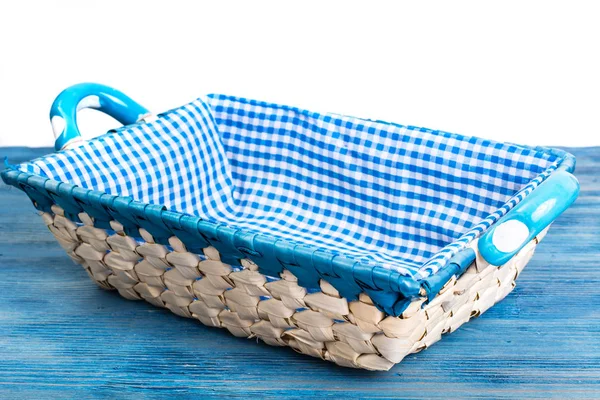 White wicker basket of bread with checkered cloth on blue backgr — Stock Photo, Image