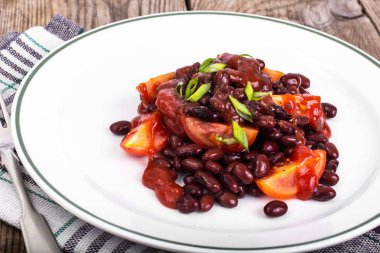 Kuru fasulye, domates, ketçap, soğan ve baharat beyaz plat üzerinde