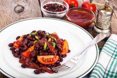 Kuru fasulye, domates, ketçap, soğan ve baharat beyaz plat üzerinde