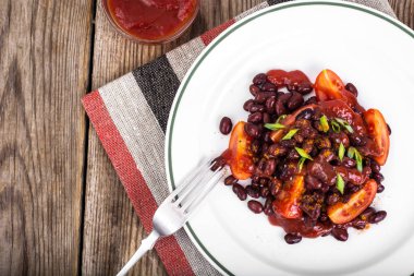 Kuru fasulye, domates, ketçap, soğan ve baharat beyaz plat üzerinde