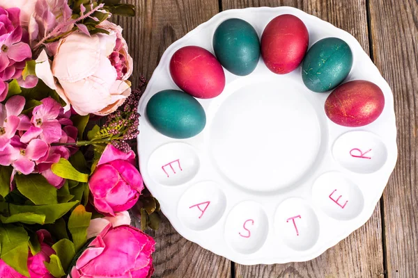 Huevos de Pascua pintados sobre plato blanco sobre fondo de madera — Foto de Stock