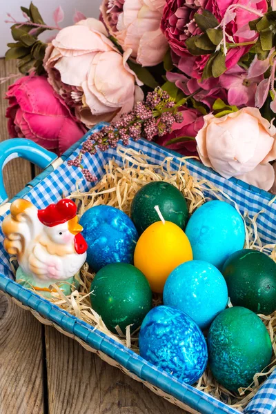 Пасхальные яйца, солома, цветы — стоковое фото