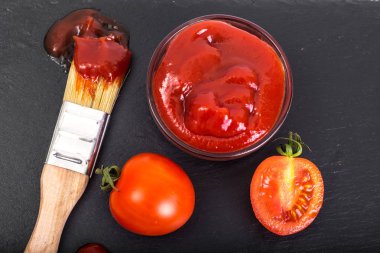 Ketçap, domates ve siyah taş zemin üzerine fırça ile kase