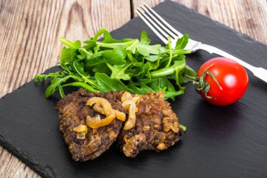 Kızarmış Karaciğer, siyah taş plaka üzerinde taze roka