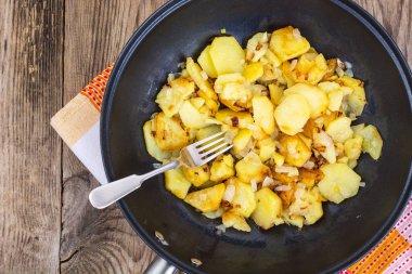 Dilimlenmiş soğan tavada ahşap backgr ile kızarmış patates