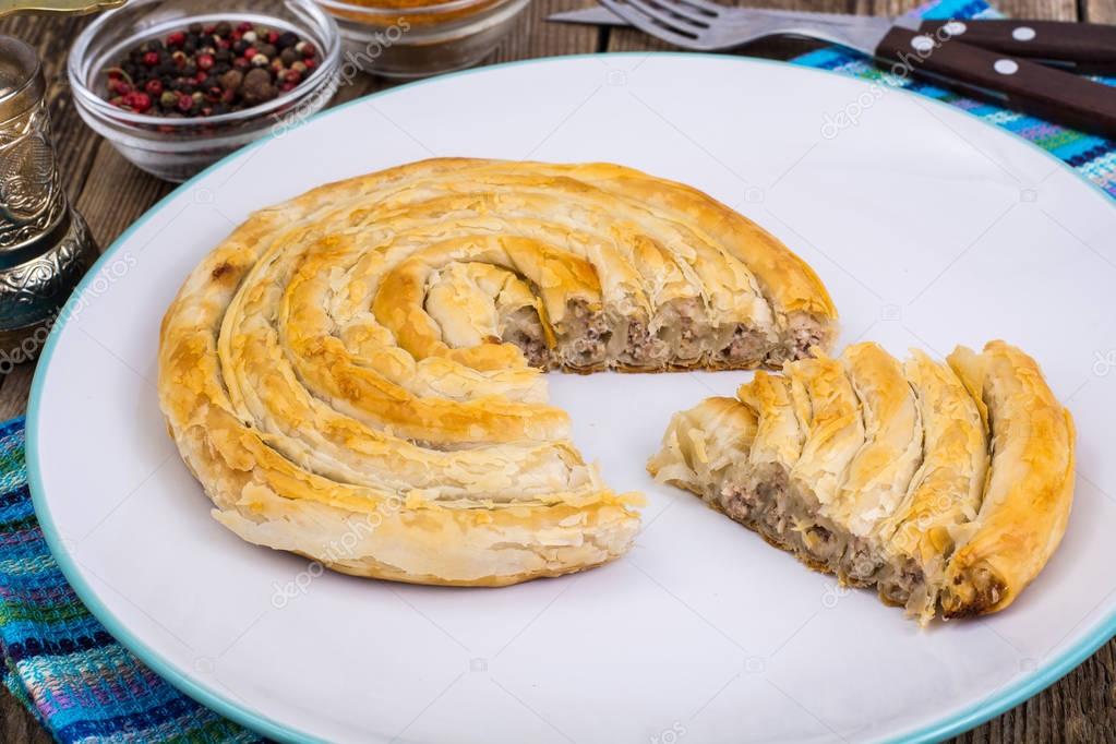 Meat burekas from puff pastry on wooden background