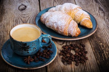 Kahve espresso ve ahşap zemin üzerine taze kruvasan