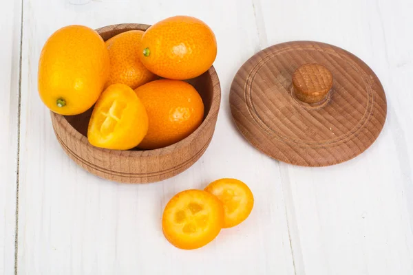 Small ripe orange kumquats on white wooden background — Stock Photo, Image