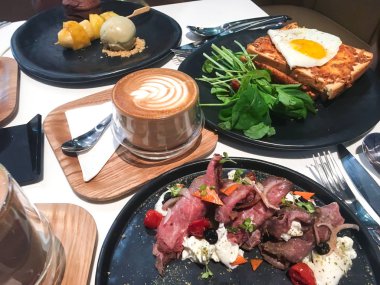 Sahanda yumurta, rucola, tost, jambon ve cappuccino kahvaltı için