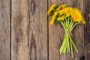 Ahşap zemin üzerine sarı dandelions demet