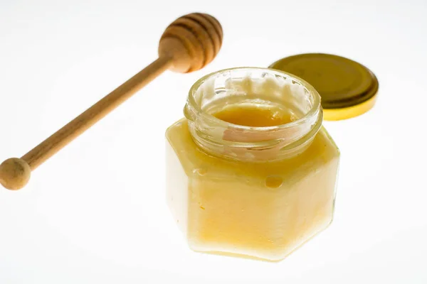 Spoon and honey in glass jar on white background — Stock Photo, Image