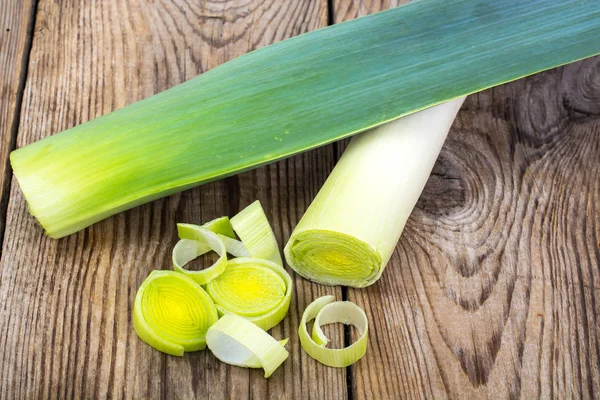 Leek, cut into pieces, on an old wooden table — Stock Photo, Image