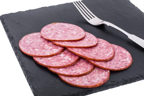 Sliced sausage on black stone plate