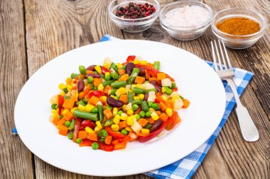 Eski ahşap masa beyaz tabağa haşlanmış sebze. Sağlıklı ve