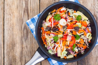 Ahşap arka plan üzerinde tavada pişmiş sebze karışımı dondurulmuş,