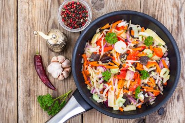 Ahşap arka plan üzerinde tavada pişmiş sebze karışımı dondurulmuş,