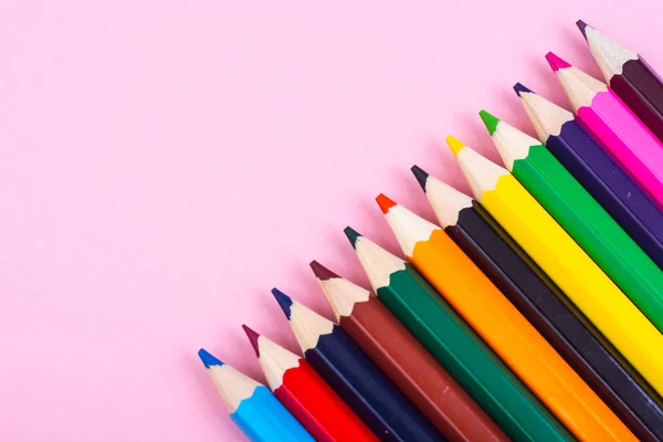 Разноцветные карандаши на фоне розовой бумаги — стоковое фото