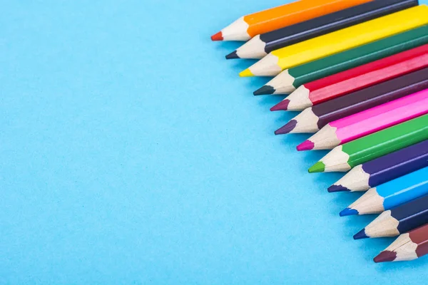 Канцелярские принадлежности: цветные карандаши на синем фоне . — стоковое фото
