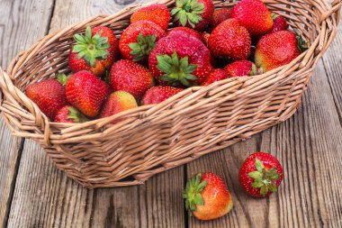 Hasır sepet ahşap arka plan üzerinde çilek