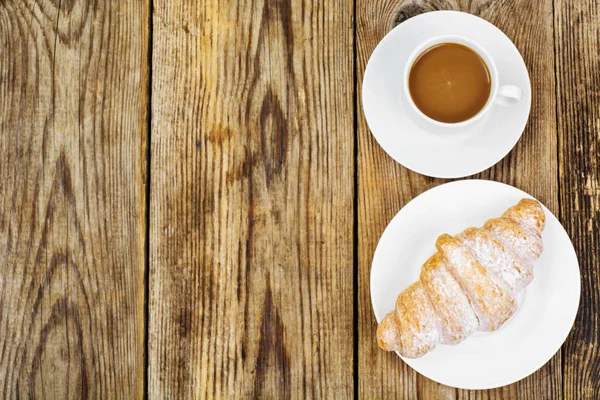 El desayuno. Croissant fresco y taza de café con leche sobre madera — Foto de Stock