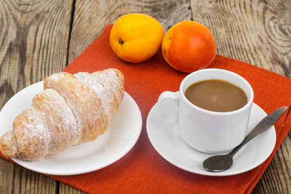 Petit déjeuner. Croissant frais et tasse de café au lait sur bois — Photo