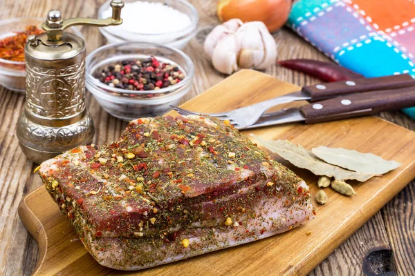 Соленый свиной бекон со специями на кухонной доске — стоковое фото
